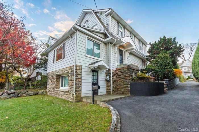 View of front of home featuring stone siding and a front lawn