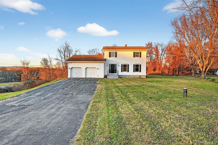 View of front facade with asphalt driveway, a front yard, and a garage