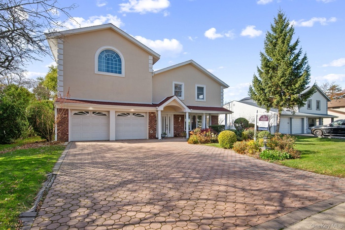 Traditional-style home featuring brick siding, stucco siding, decorative driveway, a garage, and a front lawn