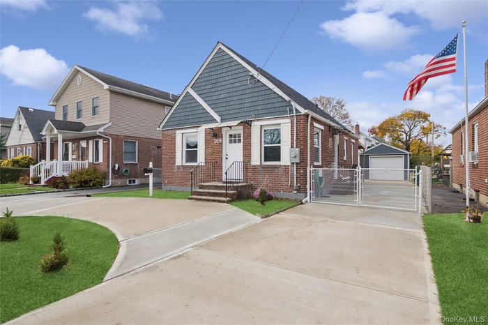 Bungalow with a gate, brick siding, a detached garage, driveway, and an outbuilding