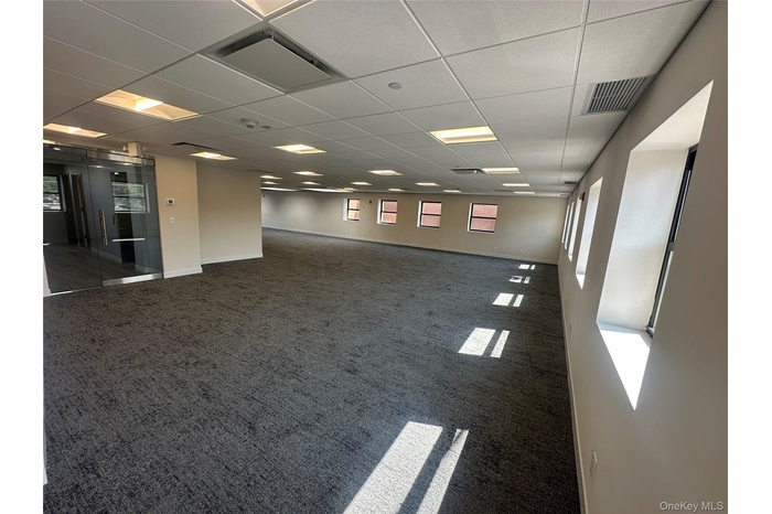 Carpeted spare room featuring a paneled ceiling and baseboards