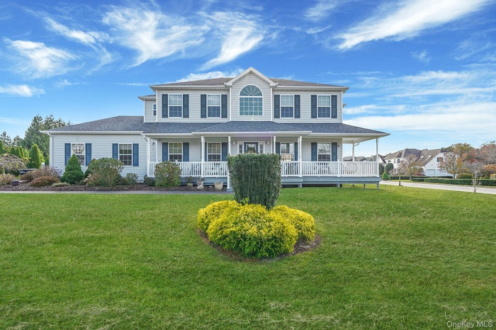 View of front of house with covered porch, a front lawn, and roof with shingles