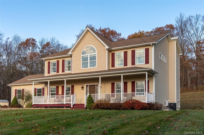 Colonial house with roof with shingles, covered porch, and a front yard