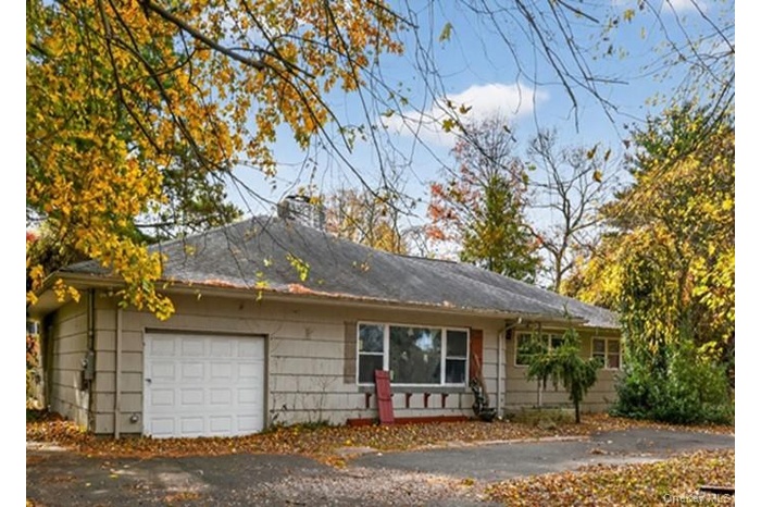 Ranch-style house with driveway, a chimney, a garage, and roof with shingles