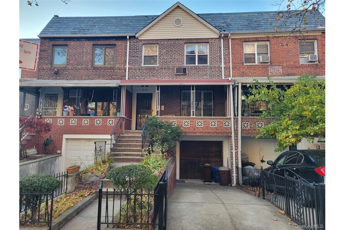 Traditional home featuring a garage, brick siding, concrete driveway, stairs, and a high end roof