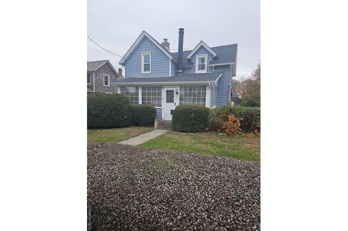 View of front of house with a chimney, a front yard, a shingled roof, and entry steps