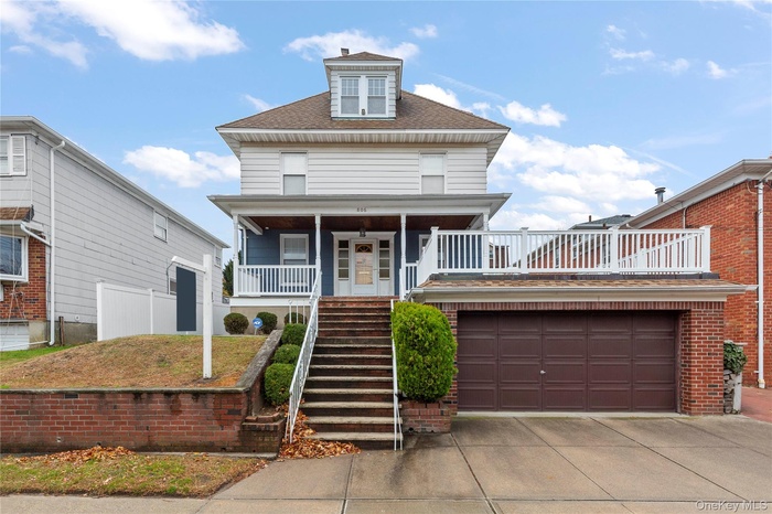 American foursquare style home with stairs, a shingled roof, covered porch, a garage, and driveway