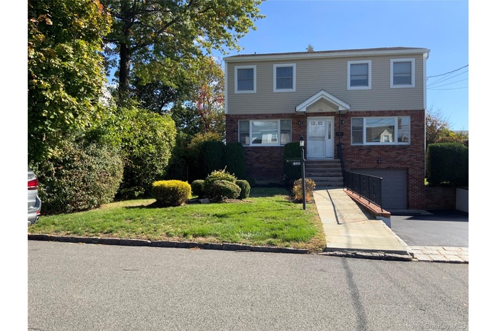 Colonial house featuring a front lawn, brick siding, asphalt driveway, and a garage