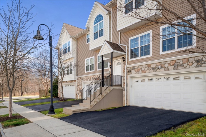 Traditional-style home with stone siding, a garage, and driveway