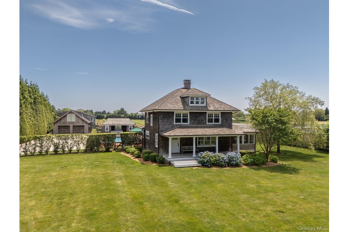 Rear view of property featuring a yard, a chimney, covered porch, and a shingled roof