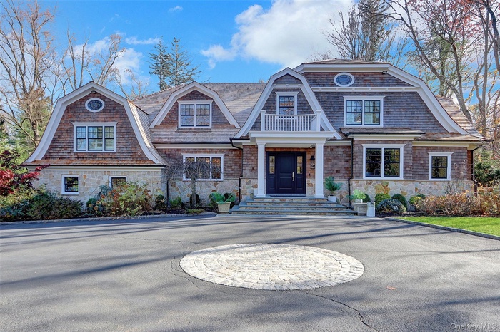 Shingle-style home featuring a gambrel roof and stone siding