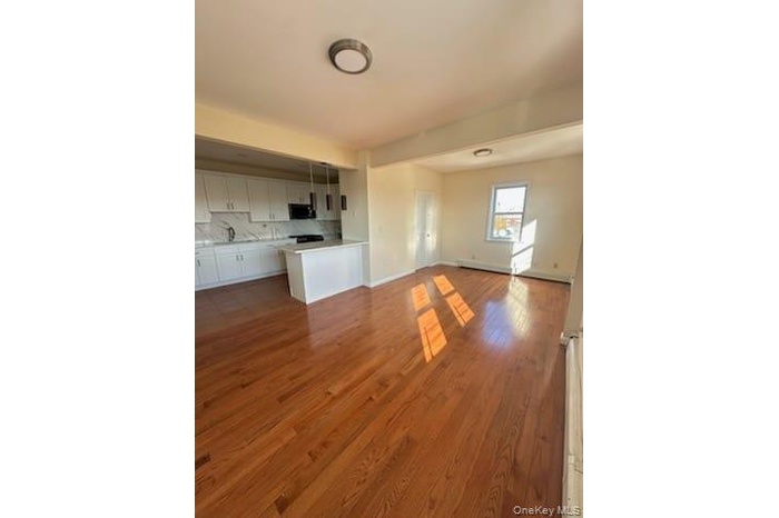 Unfurnished living room with light wood-style floors and baseboards