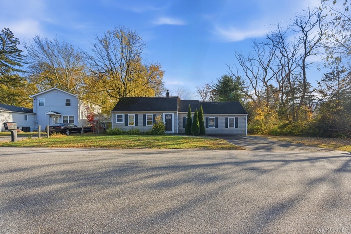 View of front facade with asphalt driveway and a front yard