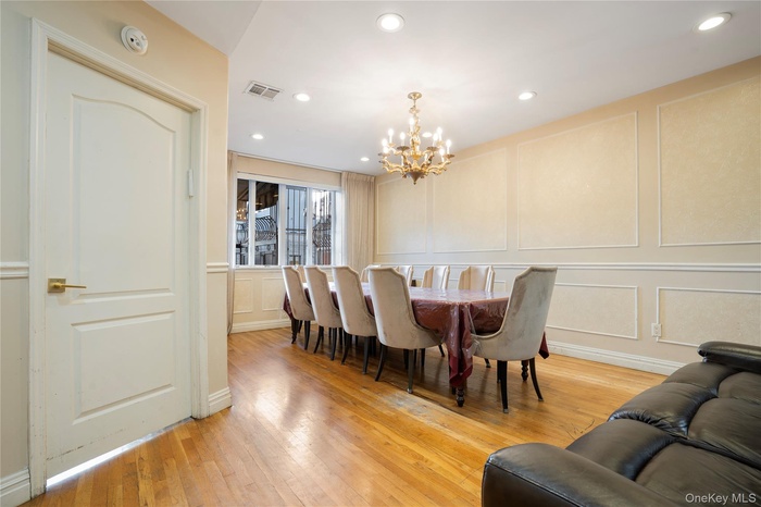 Dining room with a decorative wall, light wood-type flooring, recessed lighting, and a chandelier