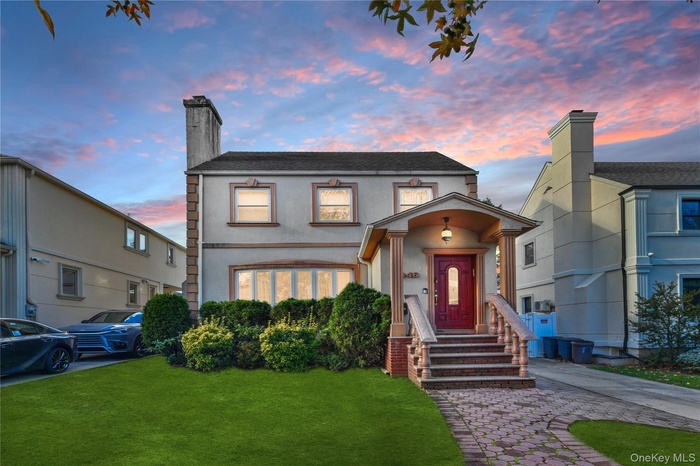 View of front facade with a lawn, stucco siding, and a chimney