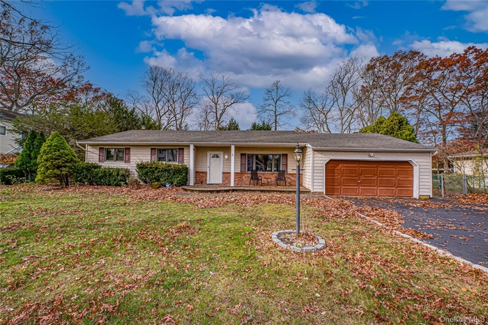 Ranch-style home with covered porch, a front yard, asphalt driveway, and a garage