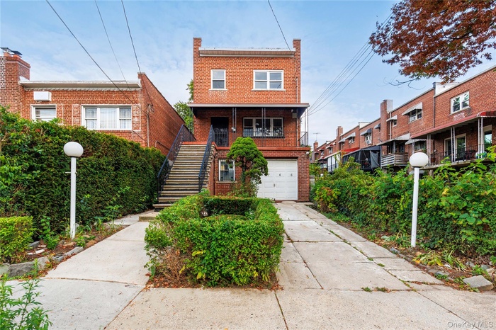 Traditional home featuring brick siding, stairs, driveway, and a garage
