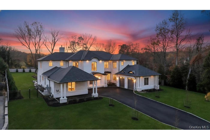 French provincial home featuring a chimney, driveway, and a garage