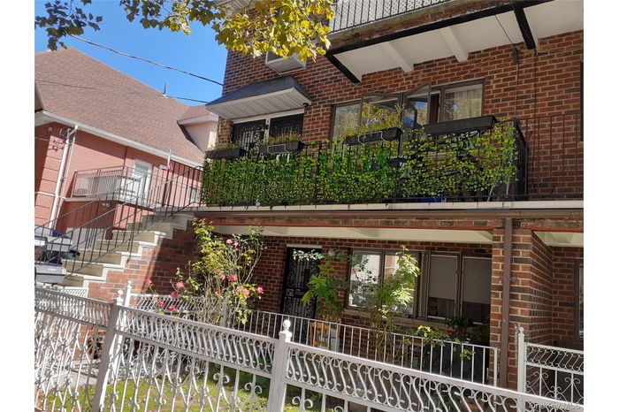 Rear view of property featuring stairs, brick siding, and a balcony