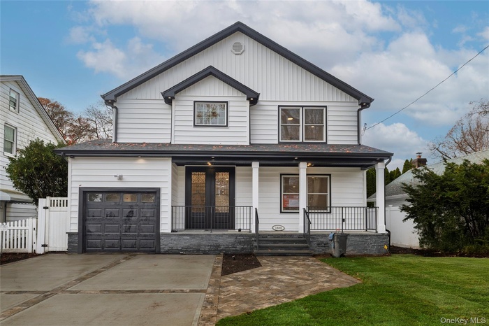 View of front of house with covered porch, board and batten siding, driveway, and a garage