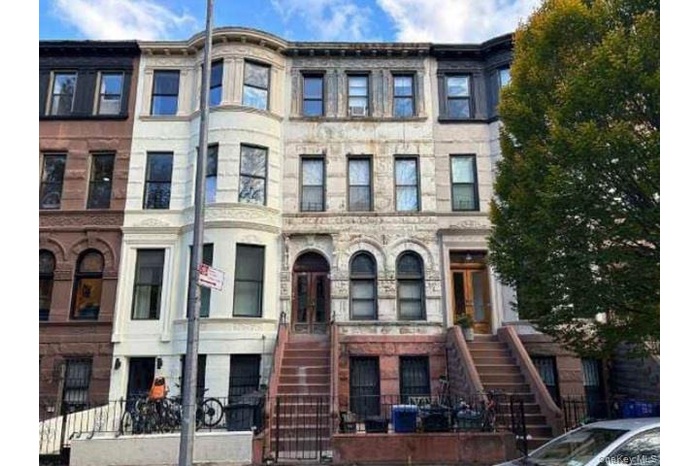 View of property featuring a fenced front yard and stairway