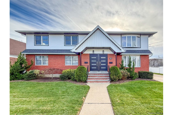 View of front of home with a front yard, brick siding, and a shingled roof