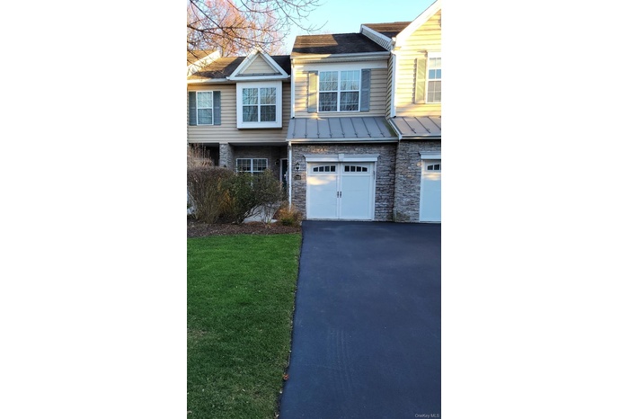 Traditional home with a standing seam roof, stone siding, asphalt driveway, and a metal roof