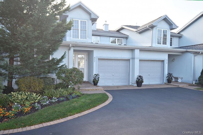 Traditional-style house featuring asphalt driveway, stucco siding, and a garage