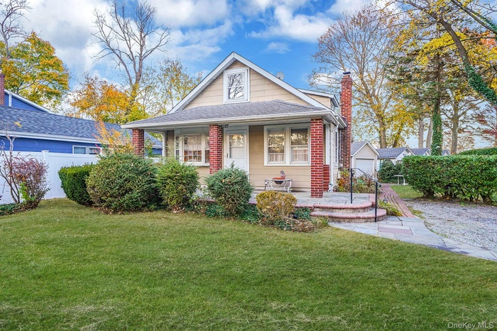 Bungalow with a porch, a chimney, brick siding, and roof with shingles