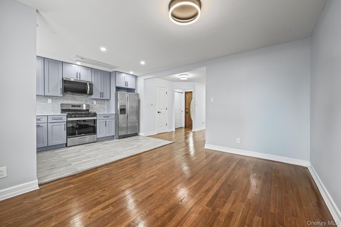 Kitchen featuring gray cabinetry, decorative backsplash, dark wood-type flooring, appliances with stainless steel finishes, and recessed lighting