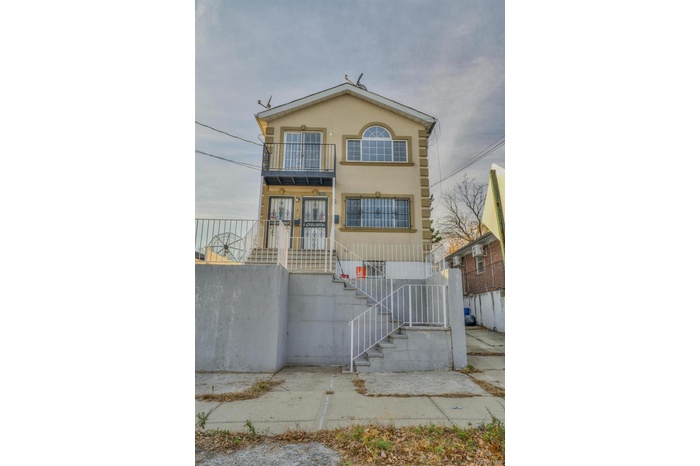 View of front of house featuring a balcony, stairs, and stucco siding