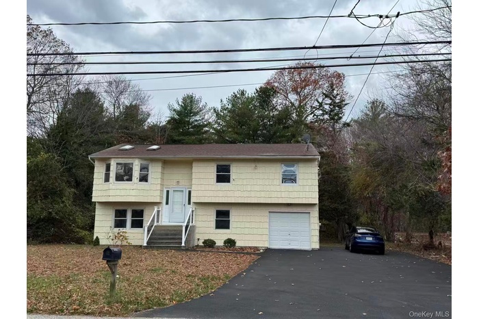 Raised ranch with asphalt driveway and a garage