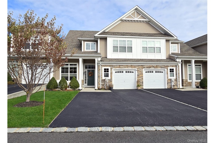 Craftsman inspired home featuring driveway, a front lawn, a garage, a shingled roof, and stone siding