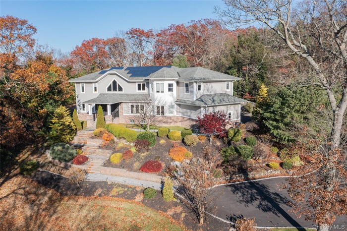 View of front of property featuring solar panels and view of scattered trees