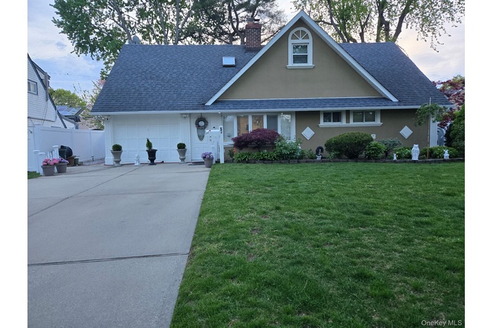 View of front of home featuring roof with shingles, concrete driveway, an attached garage, and a chimney