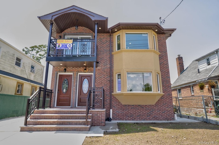 View of front facade featuring brick siding and a balcony