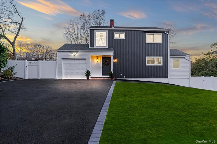 View of front of house with a gate, a chimney, a shingled roof, asphalt driveway, and an attached garage