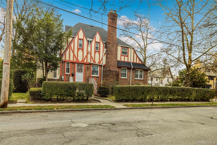 View of front of home with brick siding and a chimney