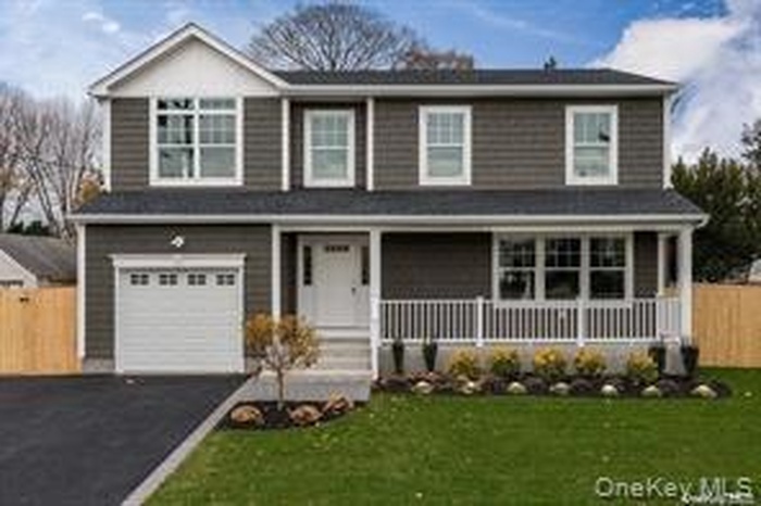Traditional-style home featuring covered porch, driveway, and an attached garage