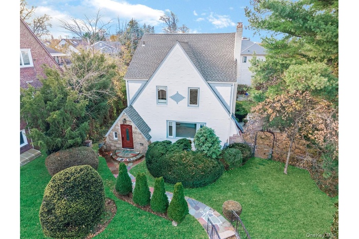 View of front of house with a chimney, roof with shingles, and a front yard