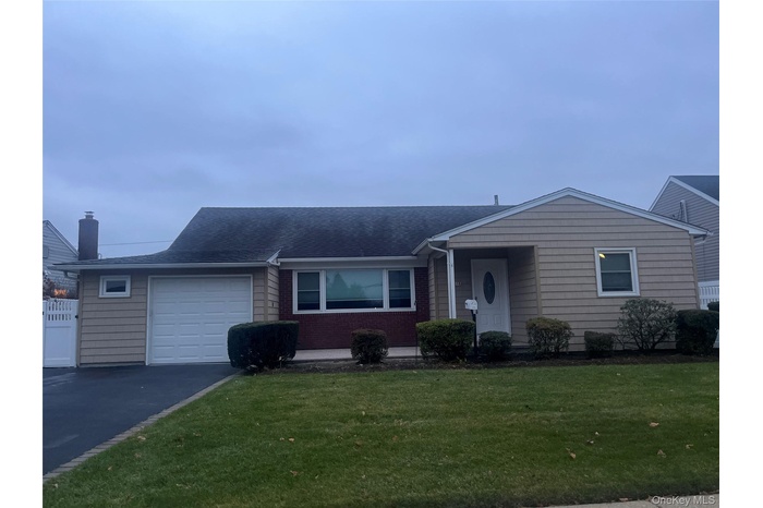 Ranch-style home featuring a front yard, roof with shingles, driveway, and an attached garage