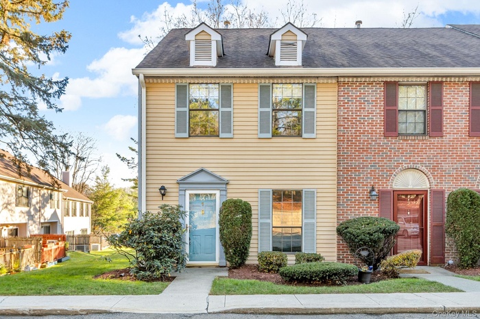 Colonial home with roof with shingles and brick siding