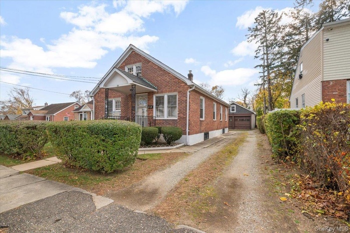 View of front of Cape with brick siding, and a detached 2 car garage on 2nd structure