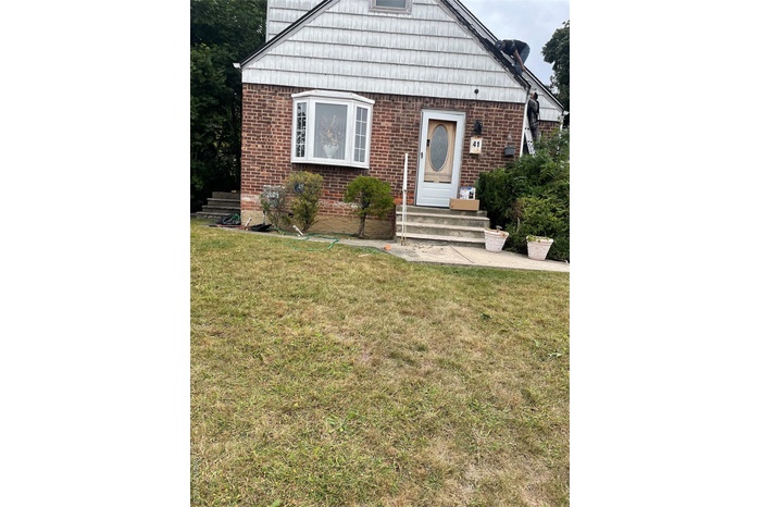 View of front of property featuring a front yard and brick siding