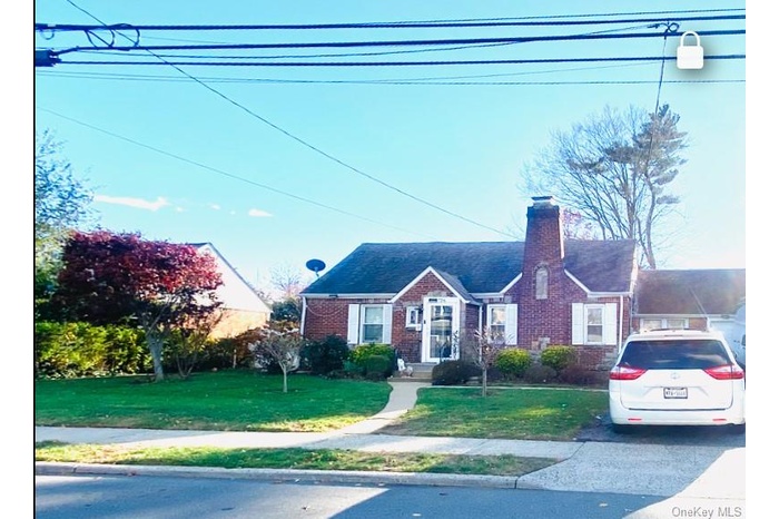 View of front of property with a front lawn, a chimney, and brick siding