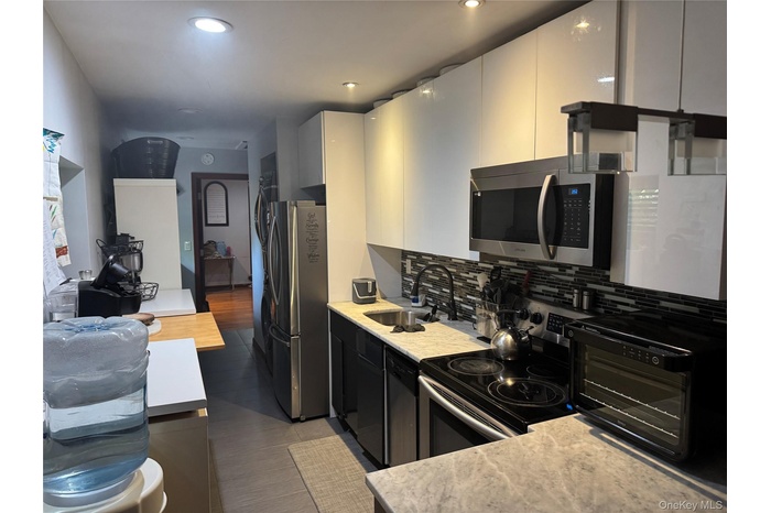Kitchen with stainless steel appliances, backsplash, white cabinetry, modern cabinets, and recessed lighting