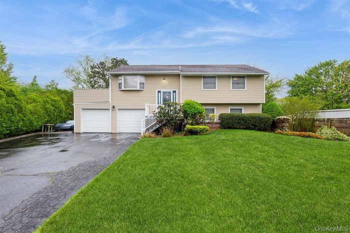 Raised ranch with driveway, a front lawn, and a garage