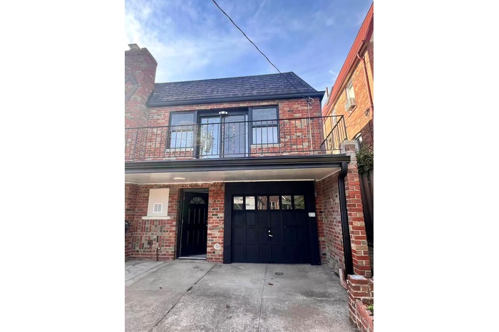 View of front of home with brick siding, a balcony, concrete driveway, and a garage