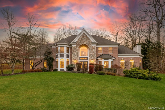 View of front of home featuring a yard, a chimney, brick siding, and stone siding