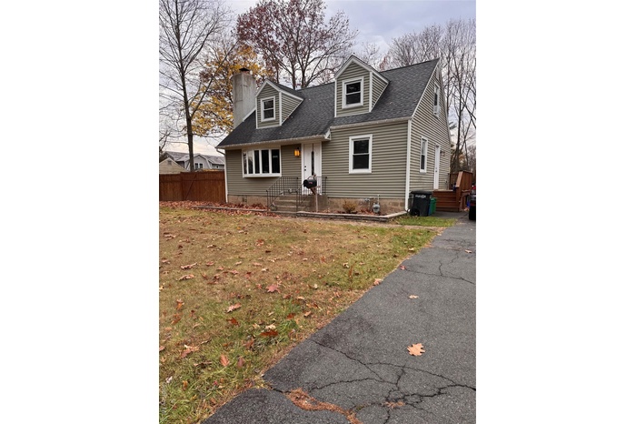 New england style home featuring a shingled roof and a chimney
